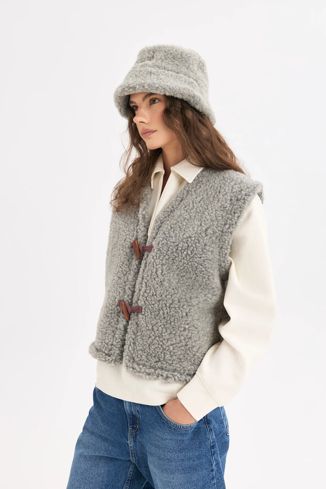 [pl][Modelka ma 179 cm wzrostu i nosi rozmiar S] [en][The model is 179 cm tall and wears size S] [de][Das Model ist 179 cm groß und trägt Größe S]  wełniana kamizelka merino szara z guzikiem merino wool vest stone grey