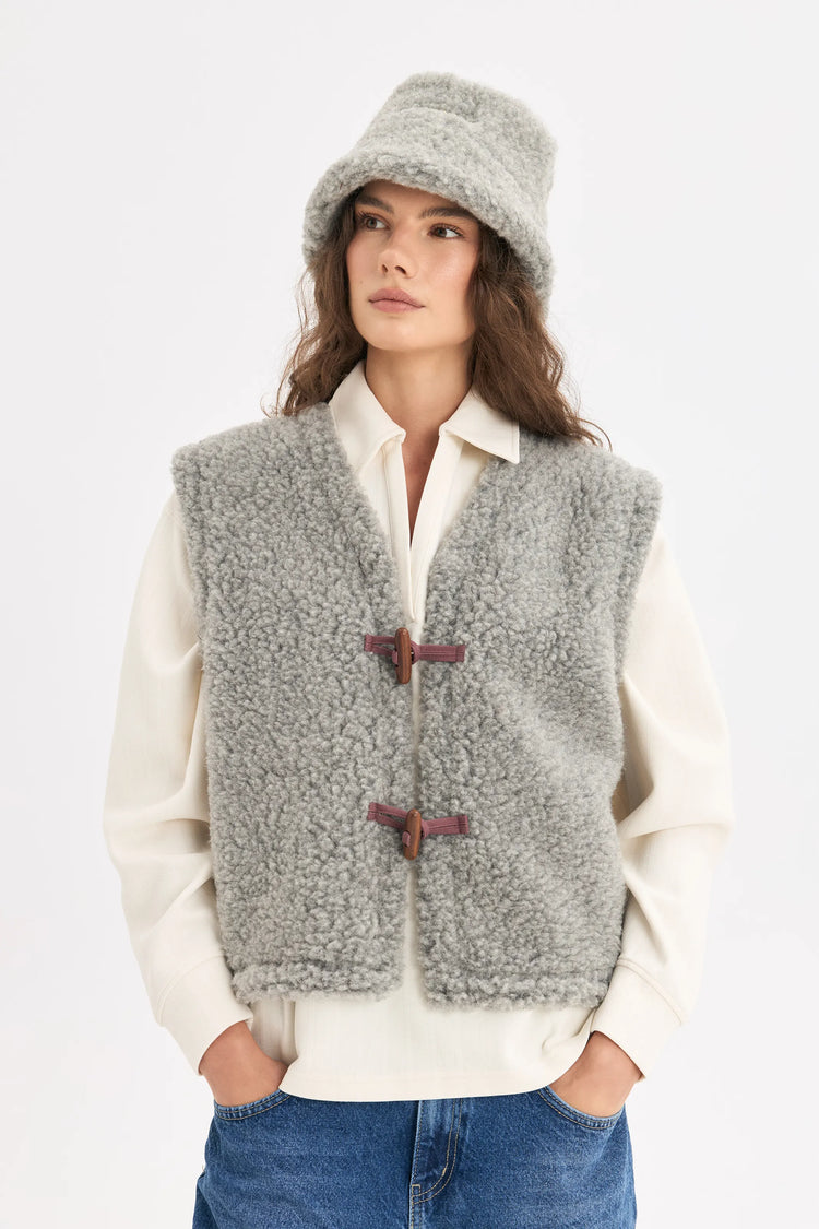 [pl][Modelka ma 179 cm wzrostu i nosi rozmiar S] [en][The model is 179 cm tall and wears size S] [de][Das Model ist 179 cm groß und trägt Größe S]  wełniana kamizelka merino szara z guzikiem merino wool vest stone grey