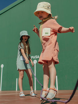 [Chloe ma 97 cm wzrostu i nosi kombinezon w rozmiarze 1-2 lata] dziecięcy kombinezon frotowy brzoskwiniowy peach bawełna organiczna organic cotton jumpsuit overall dzieci kapelusz