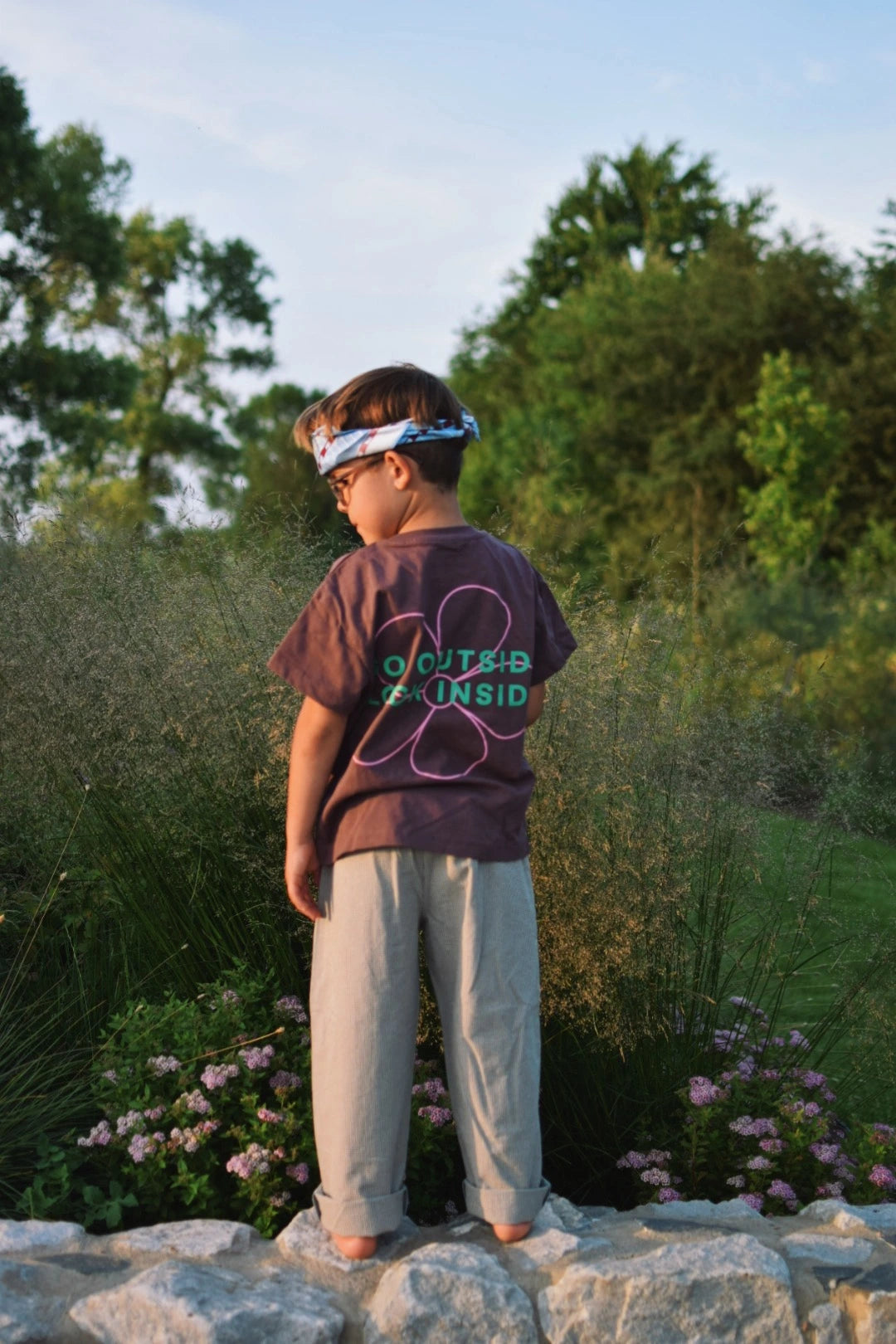 [Model ma 118 cm wzrostu nosi rozmiar 7-8 lat] spodnie w kratę dziecięce foggy brown vichy brązowe outfit stylizacja t-shirt dziecięcy brązowy flower power bawełna organiczna organic cotton 